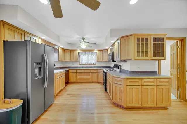 a large kitchen with stainless steel appliances granite countertop a sink refrigerator and cabinets