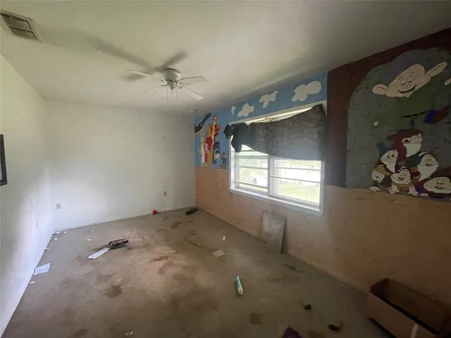 an empty room with windows and fan