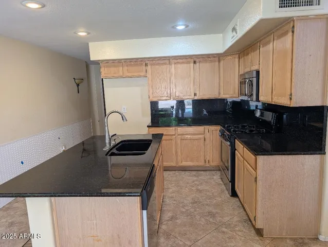 a kitchen with granite countertop a sink a stove and refrigerator