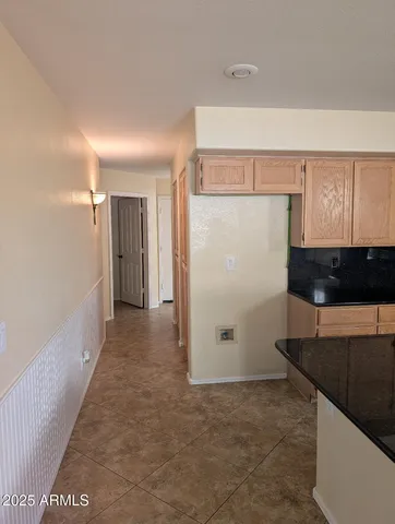 a view of a refrigerator in kitchen and an empty room