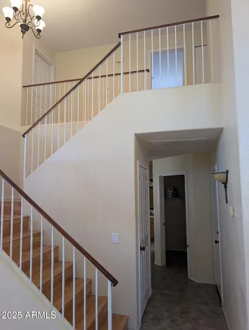 a view of staircase with railing and a chandelier