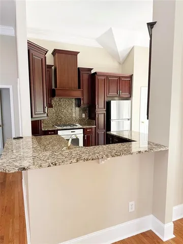a kitchen with kitchen island granite countertop a sink and a refrigerator