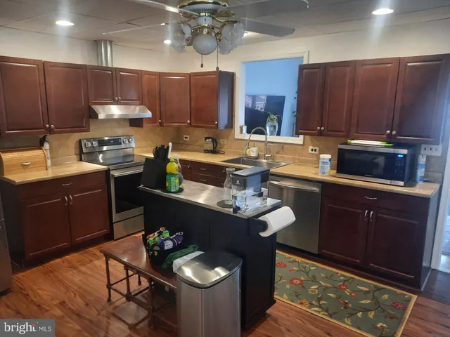 a kitchen with stainless steel appliances kitchen island granite countertop a stove refrigerator and microwave