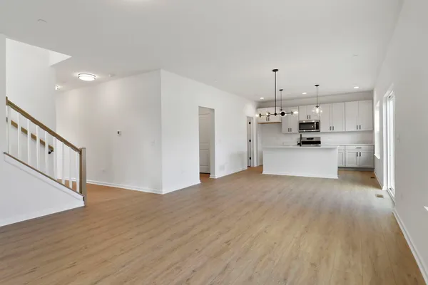 a large kitchen with kitchen island a chandelier stainless steel appliances and wooden floor