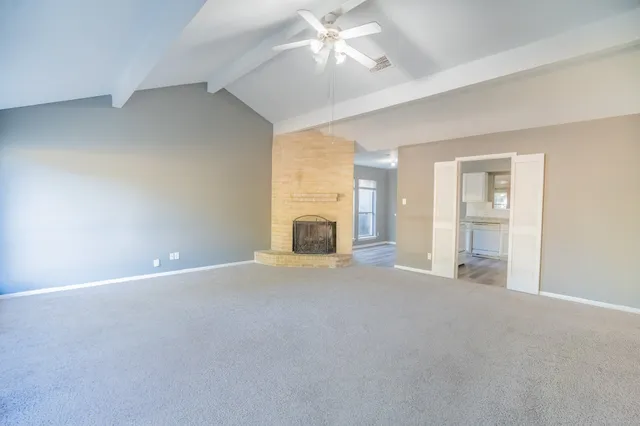 an empty room with windows and fireplace