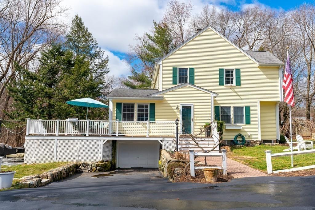 242 Old Stonebridge Road Wayland, MA 01778 - Photo 16 of 19 a view of a white house with a white wooden fence and a table and chairs under an umbrella