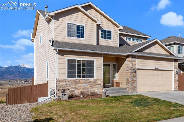 4540 Sierra Rica Road Colorado Springs, CO 80911 - Photo 6 of 42 View of front of house with a mountain view, stone siding, driveway, a garage, and a shingled roof