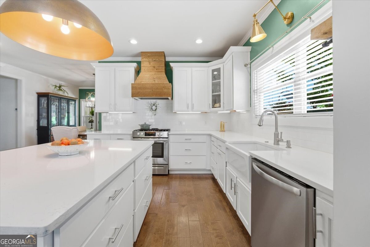 731 Markhams Drive Madison, GA 30650 - Photo 14 of 68 a kitchen with a sink dishwasher stove and white cabinets with wooden floor