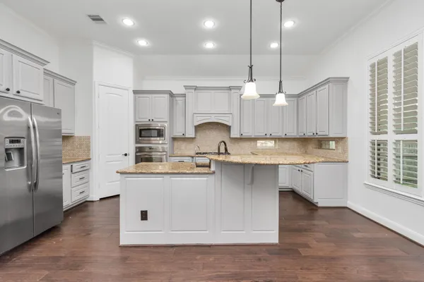 a kitchen with stainless steel appliances granite countertop a sink a stove and a refrigerator