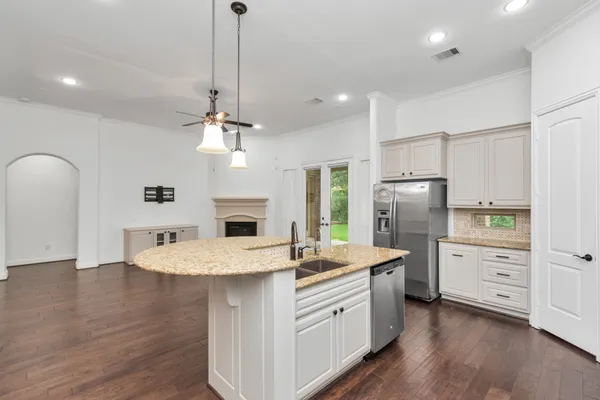 a kitchen with granite countertop a stove a sink a center island a dining table and chairs