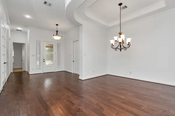 a view of a room with wooden floor chandelier and windows