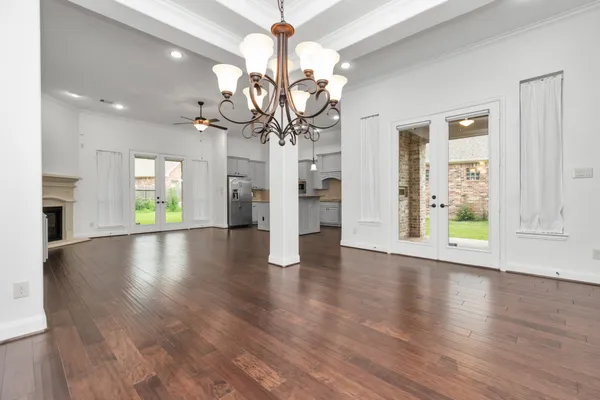 a view of an empty room with wooden floor and chandelier