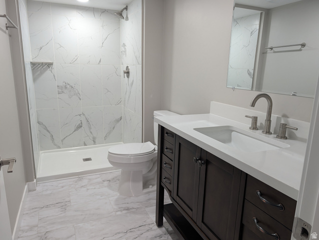 2880 Merton Way Magna, UT 84044 - Photo 18 of 30 Bathroom featuring a dark wood vanity with a white countertop and undermount sink, brushed nickel faucet, large mirror, walk-in shower with marble-look tile surround, and coordinating marble-look floor tiles