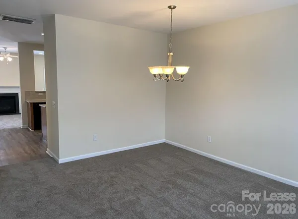 an empty room with a chandelier fan and wooden floor
