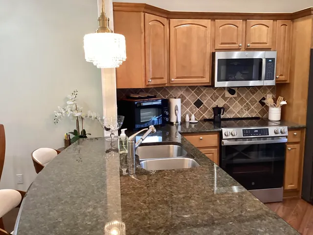 a kitchen with stainless steel appliances granite countertop a stove a sink and a microwave