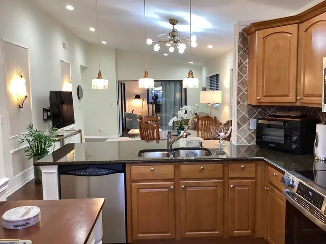 a kitchen with stainless steel appliances granite countertop a sink a stove a refrigerator cabinets and chairs