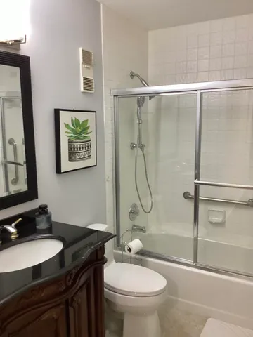 a bathroom with a granite countertop sink toilet a mirror and shower