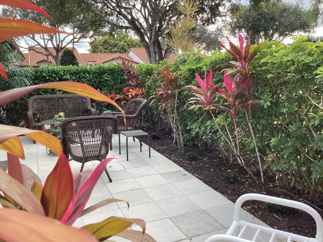 a brick house with a yard plants and large tree