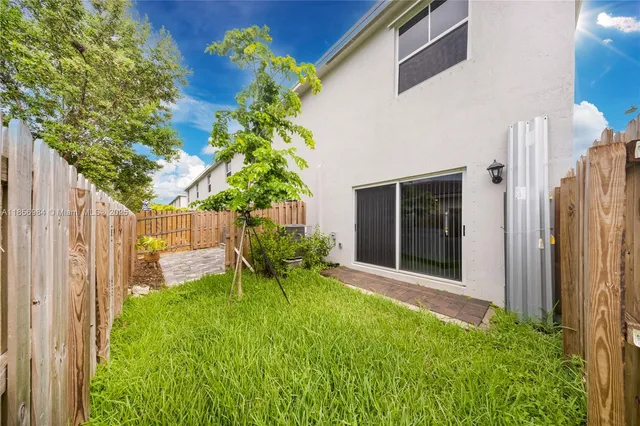 a backyard of a house with table and chairs and a large tree