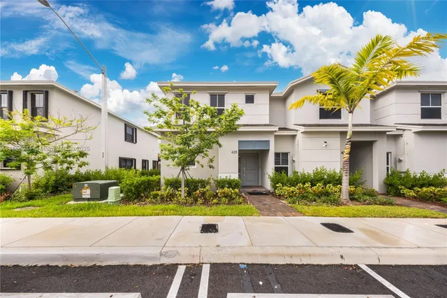 a view of a white house with a yard and potted plants