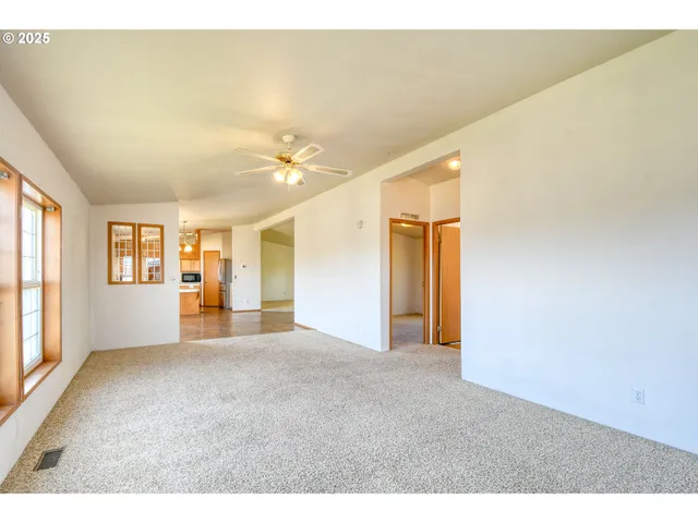 a view of a big room with windows and chandelier fan