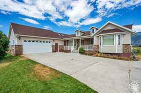 19 East Southfield Road Spanish Fork, UT 84660 - Photo 37 of 74 View of front of property featuring a porch, driveway, an attached garage, stone siding, and a front yard