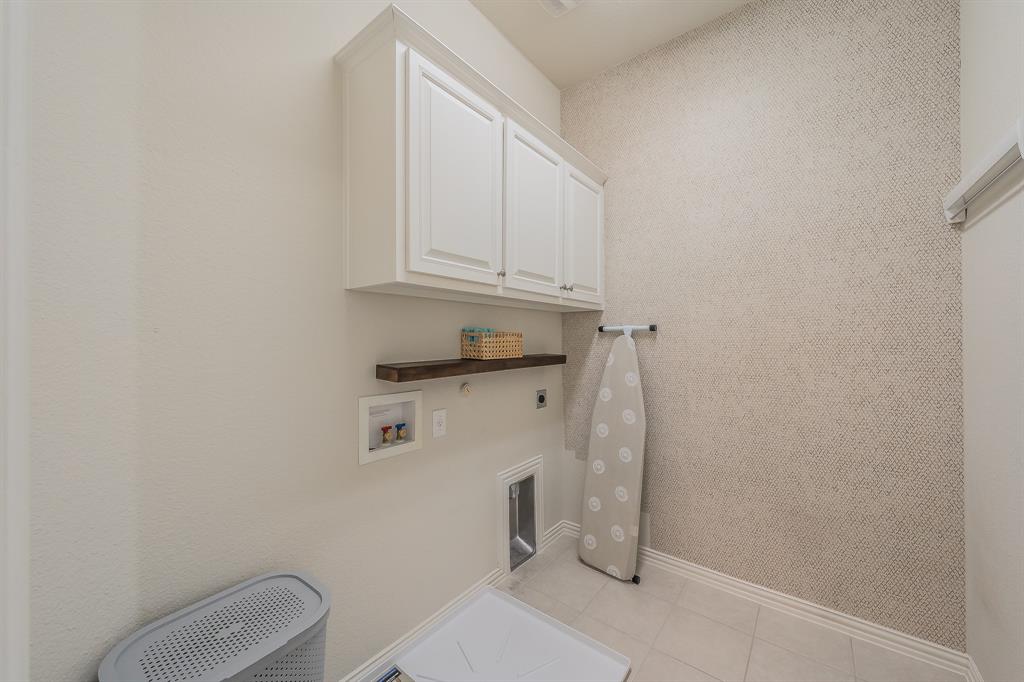 1205 Ivy Charm Way Arlington, TX 76005 - Photo 27 of 40 White cabinetry, wood-finish shelving, textured accent wall, tile flooring, and utility hookups