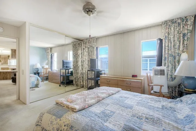 a spacious bedroom with a bed a chandelier and large windows