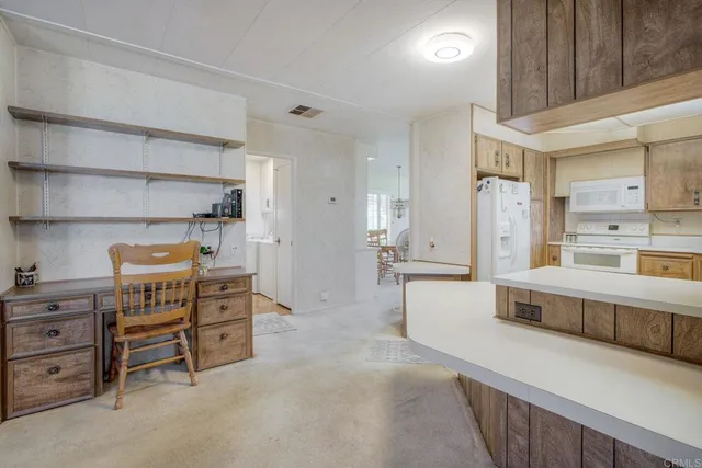 a large white kitchen with stainless steel appliances a large counter top a stove and a cabinets