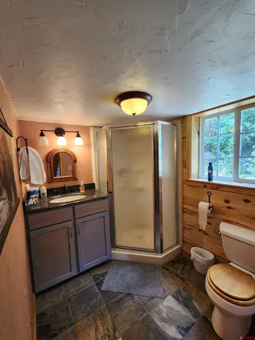 a bathroom with a granite countertop toilet a sink and a large mirror