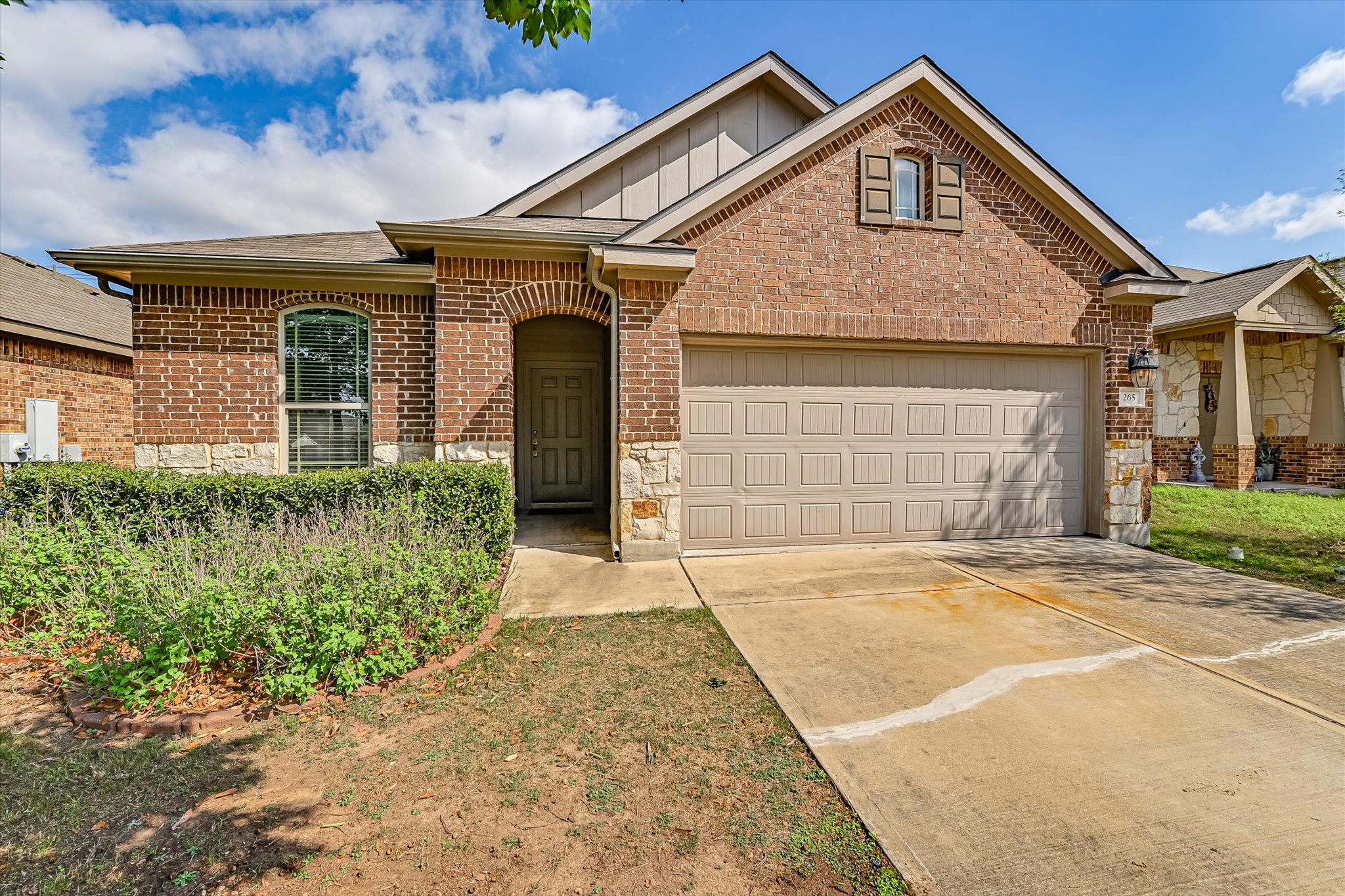 Single story home with driveway, a garage, board and batten siding, brick siding, and stone siding