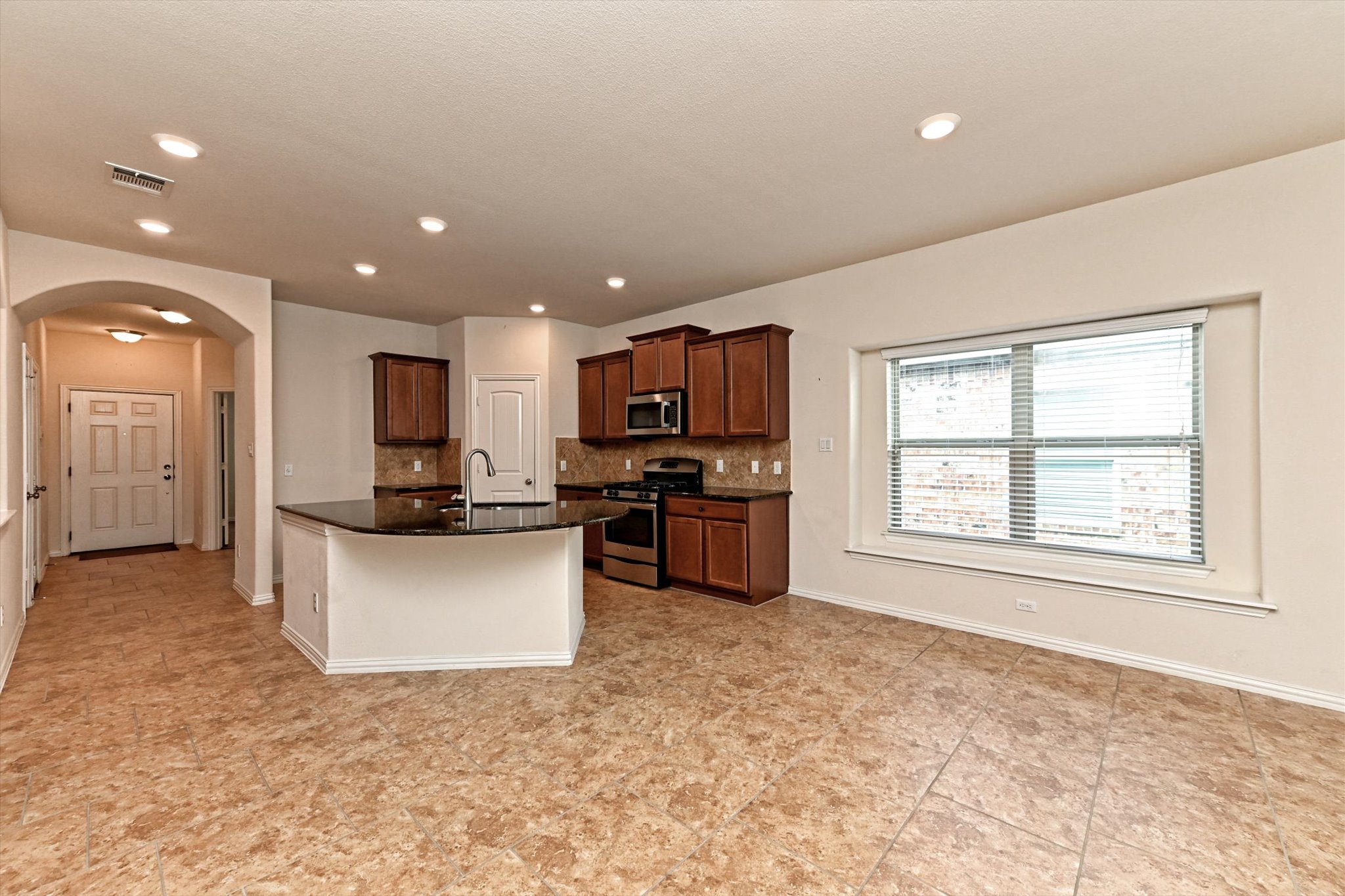 265 Shale Circle Buda, TX 78610 - Photo 5 of 29 Kitchen with arched walkways, stainless steel appliances, tasteful backsplash, dark stone countertops, and a center island with sink