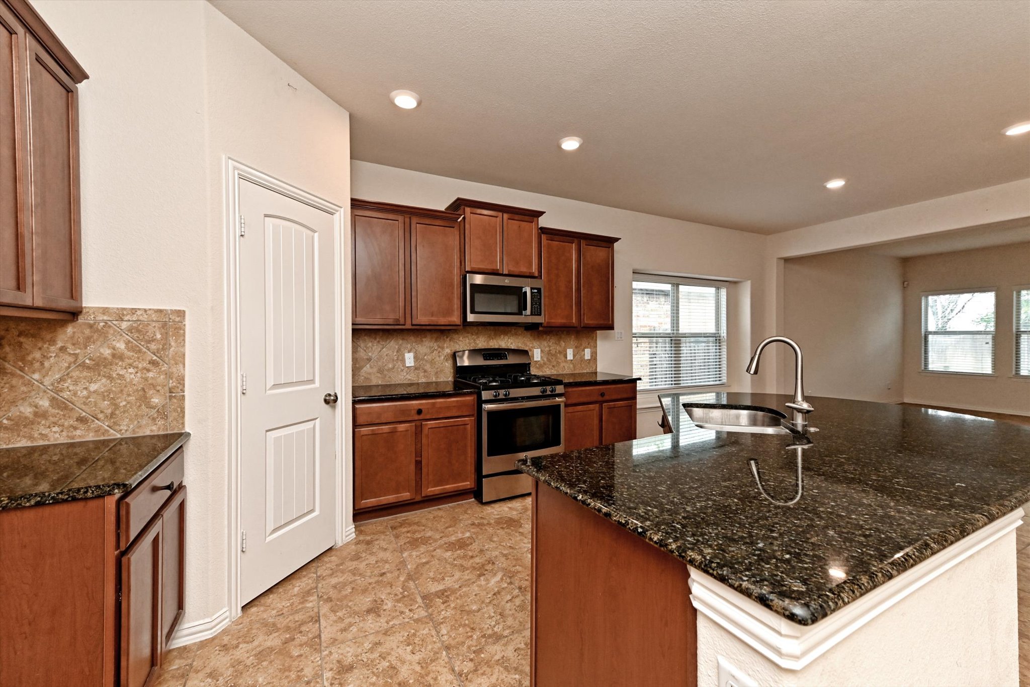 265 Shale Circle Buda, TX 78610 - Photo 7 of 29 Kitchen featuring stainless steel appliances, an island with sink, wood finish cabinetry, dark stone countertops, and recessed lighting