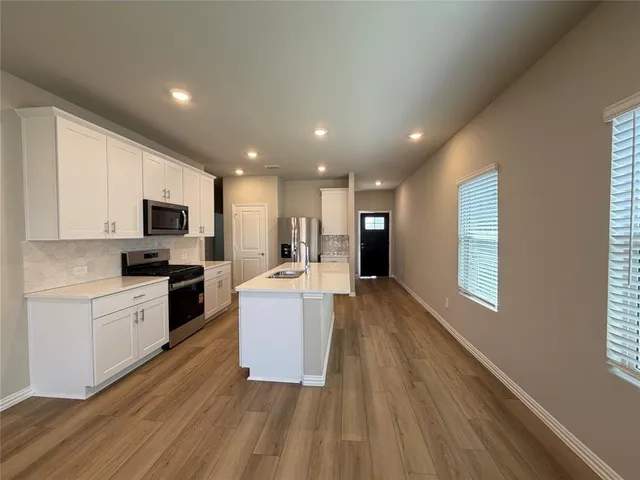 a kitchen with a sink a microwave a stove and white cabinets