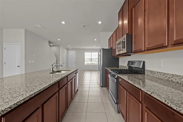 a kitchen with granite countertop stainless steel appliances a sink stove top oven and cabinets