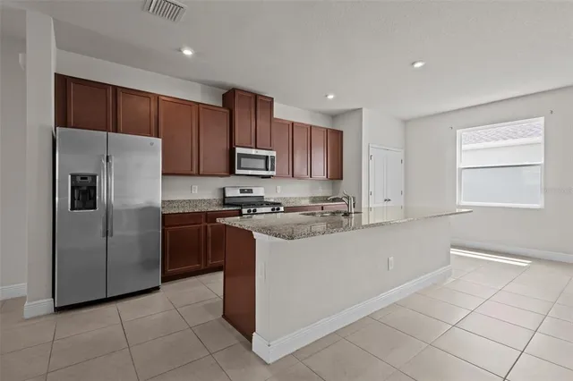 a kitchen with stainless steel appliances granite countertop a refrigerator and a stove top oven