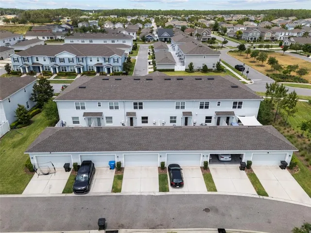 an aerial view of residential houses with outdoor space and parking