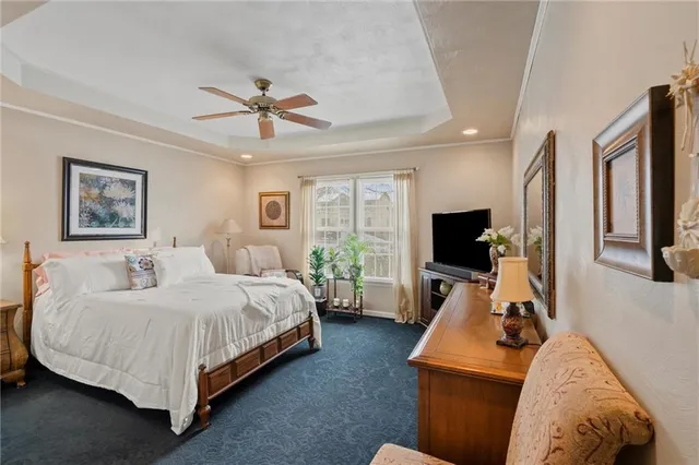 a spacious bedroom with a bed a couch and a flat tv screen on the dresser