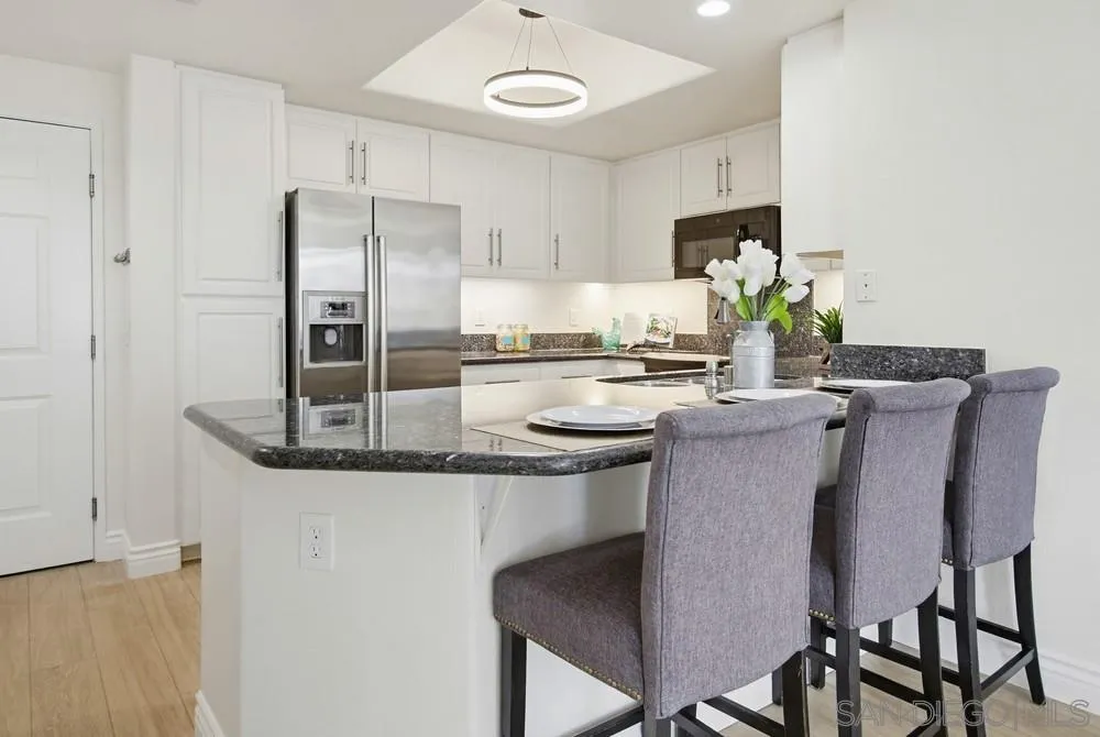 9229 Regents Road, Unit L206 La Jolla, CA 92037 - Photo 8 of 29 a kitchen with stainless steel appliances granite countertop a table chairs stove and refrigerator