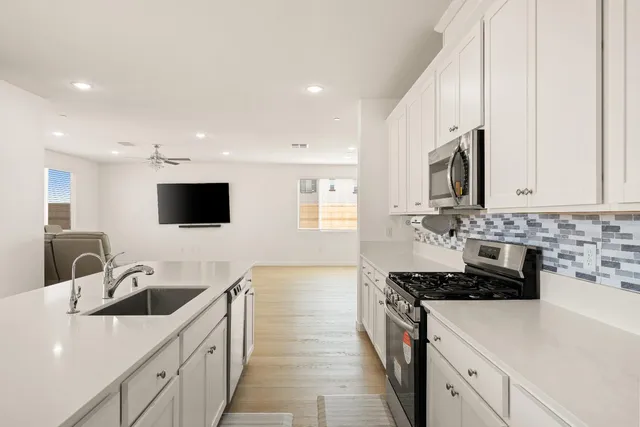 a large white kitchen with a stove a sink a microwave and island