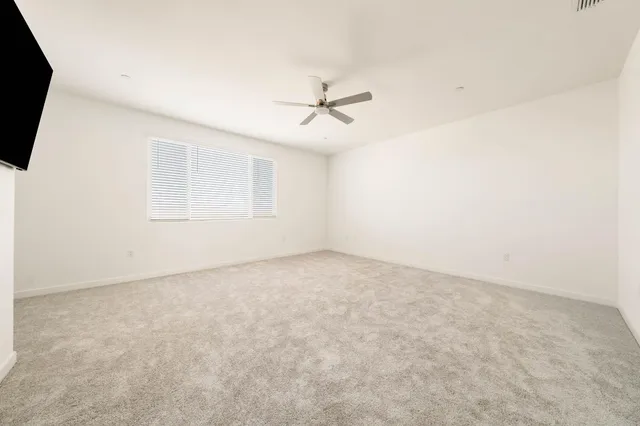 an empty room with windows and ceiling fan