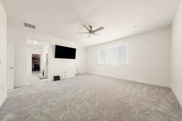 an empty room with windows and a ceiling fan