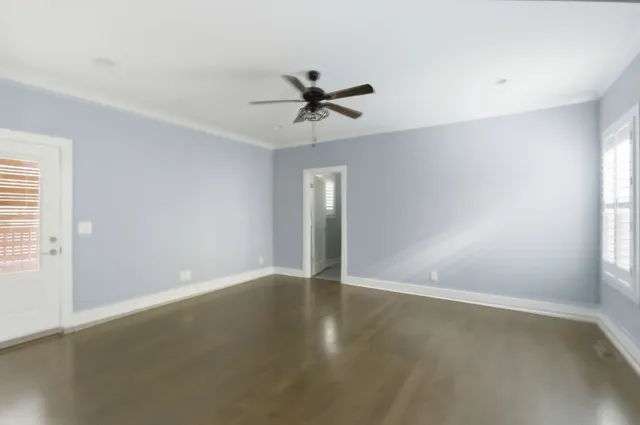 a view of an empty room with wooden floor and a ceiling fan
