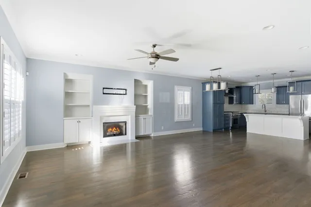 a view of a livingroom with a fireplace a ceiling fan and windows