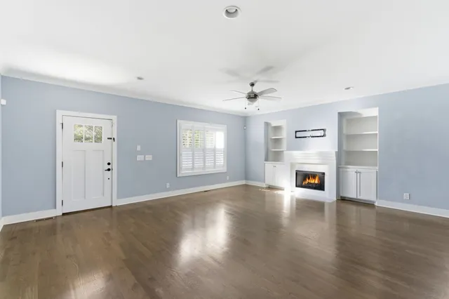 a view of an empty room with a window and wooden floor