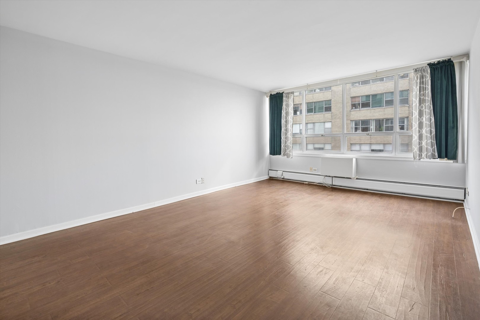6171 North Sheridan Road, Unit 2104 Chicago, IL 60660 - Photo 6 of 18 wooden floor in an empty room with a window