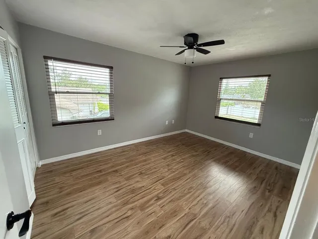 a view of an empty room with wooden floor and a window
