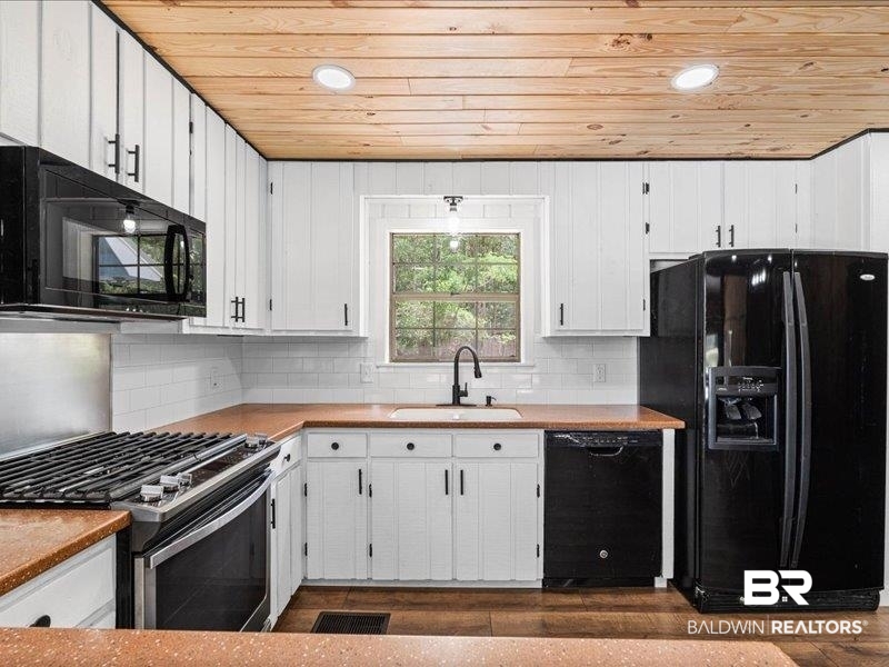 3160 Old Castleberry Road Brewton, AL 36426 - Photo 8 of 36 Kitchen featuring wood-finish flooring, wood plank ceiling, white shaker-style cabinetry, and dark countertops