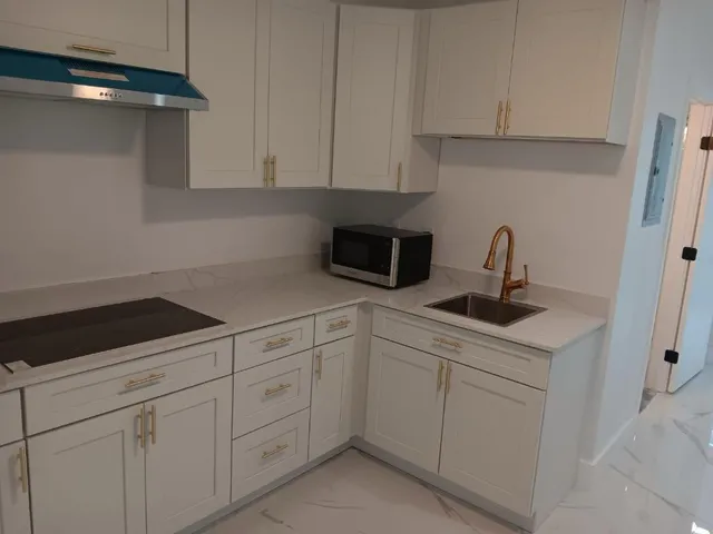 a kitchen with white cabinets sink and dishwasher