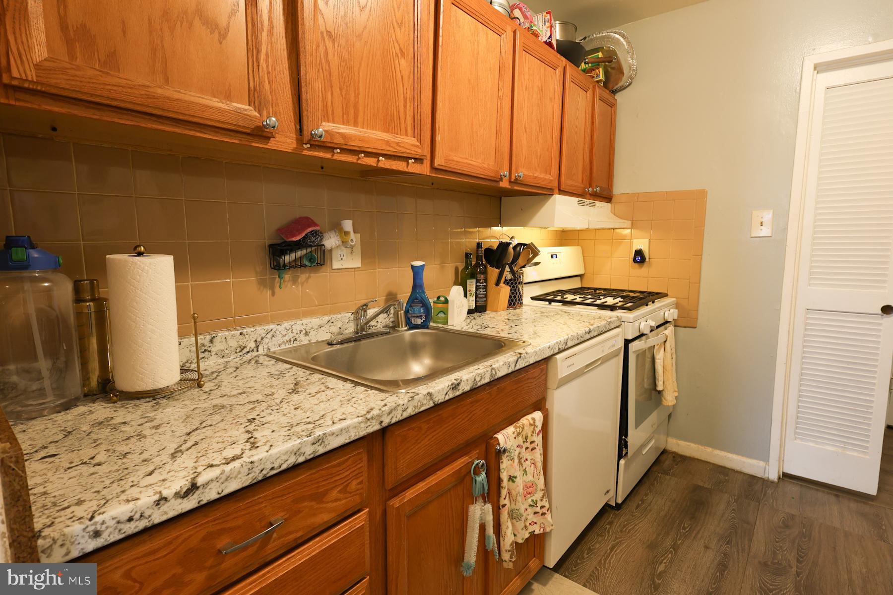 7232 Donnell Place, Unit D District Heights, MD 20747 - Photo 5 of 23 a kitchen with granite countertop a sink a stove and a wooden cabinets